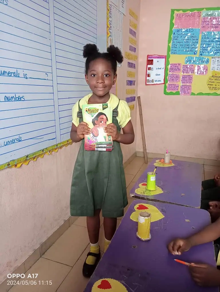 A classroom moment with a child proudly holding Rhapsody of Realities for Kids.