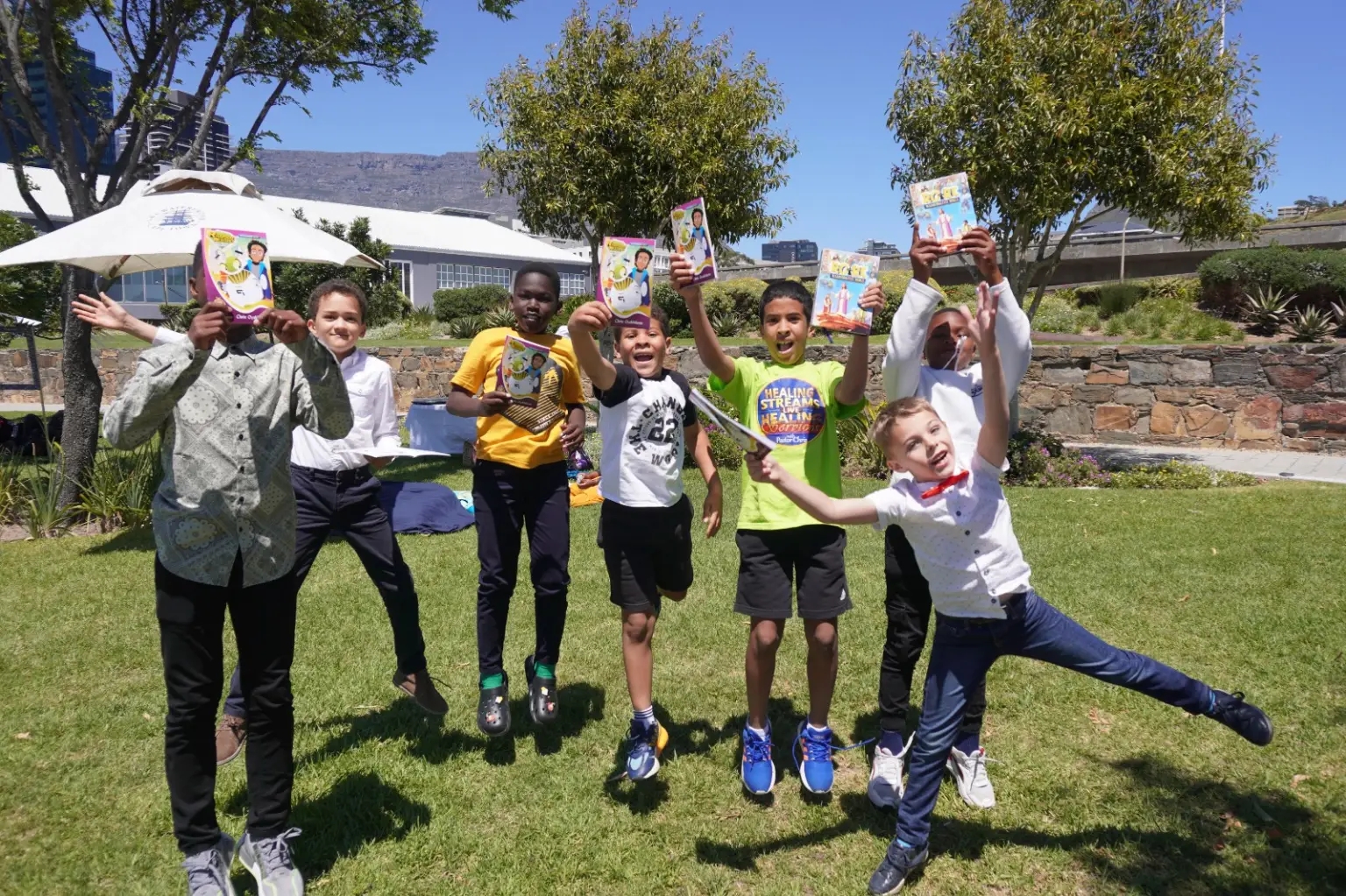 Children celebrating with Rhapsody materials in an open outdoor setting.